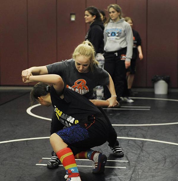 Rainier girls wrestling coach Cassie Scogin, top, works with Sequoia Miller, a seventh grader training with the Yelm High School wrestlers.